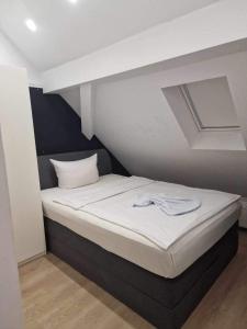 Ferienwohnungen Löwe في Königsbach-Stein: سرير في غرفة صغيرة مع مرتبة بيضاء