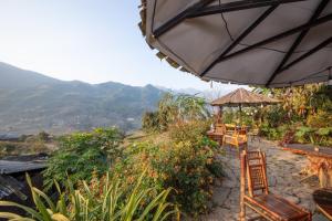 a patio with tables and chairs and an umbrella at Zili Homestay in Sa Pa
