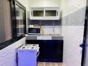 a small kitchen with a stove and a microwave at 2 ch • WiFi • 5min de la gare TER in Dakar