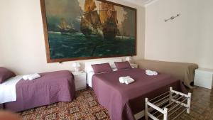 カターニアにあるCortile Stesicoroのベッド2台が備わる客室で、壁には絵画が飾られています。