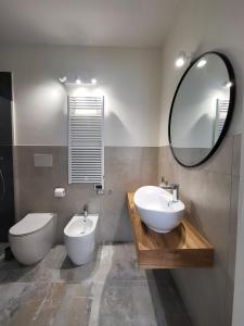 ein Badezimmer mit einem Waschbecken, einem WC und einem Spiegel in der Unterkunft Le stanze di Diana in Cesenatico