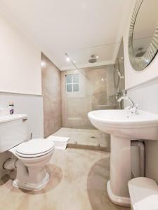 a white bathroom with a toilet and a sink at Hebron Haven Hotel in Dargle