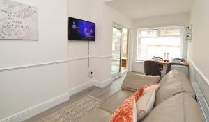 un salon avec un canapé et une télévision au mur dans l'établissement Eastbourne Beautiful Seafront house, à Eastbourne