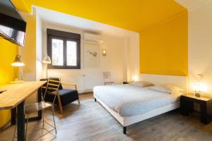- une chambre avec des murs jaunes, un lit et un bureau dans l'établissement Maison Mondrian, à Mulhouse
