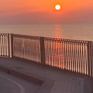 a sunset over the ocean with a bench on a balcony at Suite ortigia vista mare in Syracuse