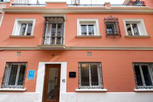 un edificio anaranjado con ventanas con barrotes y una puerta en Suites Maestranza Santas Patronas - Penthouse with jacuzzi and parking, en Sevilla