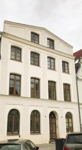 a white building with windows and cars parked in front of it at Hansestübchen in Wismar