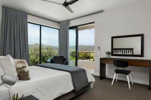 Schlafzimmer mit einem Bett, einem Schreibtisch und Fenstern in der Unterkunft Sunset Splendour Guesthouse in Noordhoek