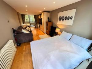 a bedroom with a large white bed and a couch at Excellent River Thames View Entire Apartment in London