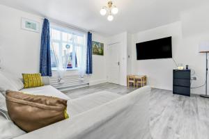 a living room with a couch and a tv at Family House in the Heart of Hanwell with 5 stars! in London