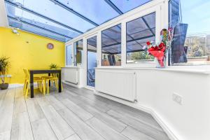 a conservatory with a table and a vase of flowers at Family House in the Heart of Hanwell with 5 stars! in London