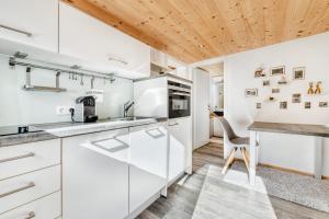 uma cozinha com armários brancos e um tecto de madeira em Ferienwohnung Zweisamkeit em Brand
