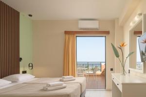 a hotel room with two beds and a balcony at Asterias Village in Hersonissos