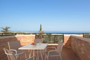 una mesa blanca y sillas en un balcón con vistas al océano en Asterias Village en Hersonissos