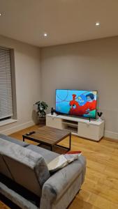 London Spacious Apartment في برينتفورد: غرفة معيشة مع أريكة وتلفزيون بشاشة مسطحة