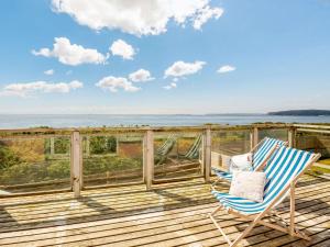 a rocking chair on a deck with a view of the ocean at 3 Bed in Pwllheli 89023 in Pwllheli