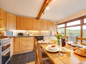 a kitchen with wooden cabinets and a table with food at 2 Bed in South Molton 88992 in Bishops Nympton