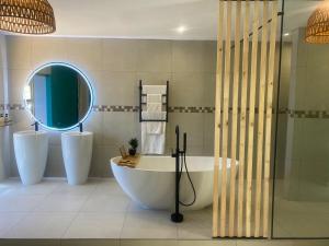 ein Badezimmer mit einer Badewanne, 2 Waschbecken und einem Spiegel in der Unterkunft Club Cocomo in Hartbeespoort