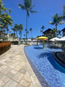 a pool at the resort with palm trees and umbrellas at Marulhos Resort Flat E205 in Porto De Galinhas
