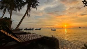 a sunset over a body of water with boats at sunset beach house in Phu Quoc