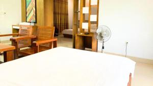 Cette chambre comprend un lit blanc, des chaises et un ventilateur. dans l'établissement Nhà Khách 206 đà nẵng, à Đà Nẵng
