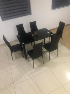- une table à manger et des chaises noires dans la chambre dans l'établissement WILLS COURT, à Accra