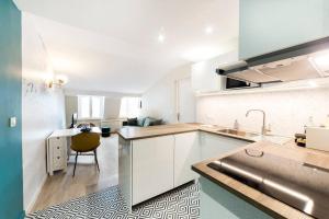 a kitchen with white cabinets and a sink and a table at Nid douillet avec vue in Lyon