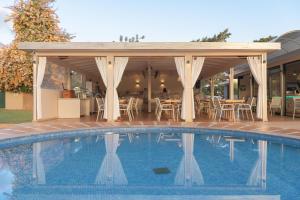 - une piscine avec un kiosque, une table et des chaises dans l'établissement Asterias Village, à Chersónissos
