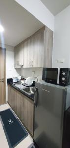 eine Küche mit einem Kühlschrank aus Edelstahl und einer Mikrowelle in der Unterkunft C Place - Capsule A in Manila
