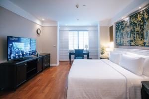 a hotel room with a large bed and a television at Grande Centre Point Hotel Ratchadamri Bangkok in Bangkok