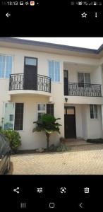 a white house with a balcony and a tree in front of it at WILLS COURT in Accra