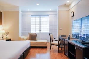 曼谷的住宿－曼谷拉查丹利中心酒店，一间卧室配有一张床、一张书桌和一台电视。