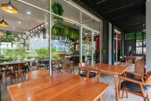 un restaurante con mesas y sillas de madera y ventanas en Urbanview Hotel Ellegan Residence Alam Sutera Serpong, en Kampungklapa 2