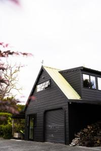 a black house with a garage at Forest Waters Bungalow in Haruru