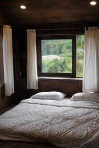 Schlafzimmer mit einem großen Bett und einem Fenster in der Unterkunft Olive Cottage Bao Loc in Tang Jran Dring