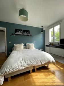 1 dormitorio con 1 cama grande y pared azul en Grand Appartement proche Paris, en Sèvres