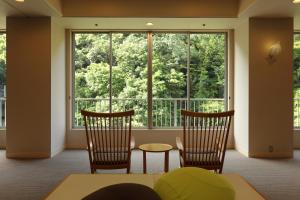 a room with two chairs and a large window at Hakone Pax Yoshino in Hakone