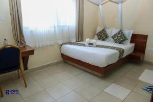 een slaapkamer met een bed, een bureau en een raam bij Hotel Cavallino in Kakamega