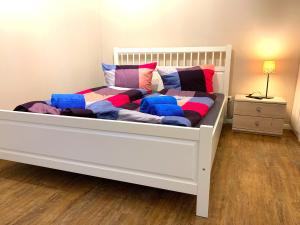 - un lit blanc avec des couvertures et des oreillers colorés dans l'établissement Ferienwohnungen Arp "Beach House" mit Terrasse und Parkplatz, à Itzehoe