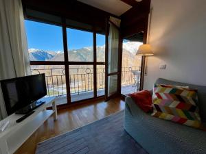 Sala de estar con sofá, TV y montañas en C18 - Alojamiento Mirador de Cerler - Villmor, en Cerler