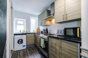 a kitchen with wooden cabinets and a washer and dryer at Creative Cottage 4 BR PrimeStay in Bolton