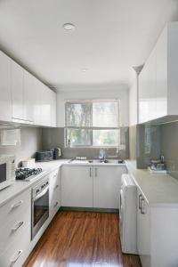 a kitchen with white cabinets and a wooden floor at Comfortconvenience 2-bedroom Unit For Families in Perth