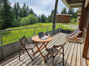 einem Holztisch mit zwei Stühlen und einem Laptop auf einer Terrasse in der Unterkunft Chamrousse, 50m piste, wifi +, terrasse vue sapins in Chamrousse