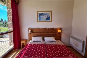 una camera con un letto con una coperta rossa di Chamrousse, 50m piste, wifi +, terrasse vue sapins a Chamrousse