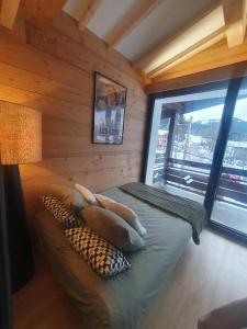 Habitación con cama con almohadas y ventana en Appartement le StelO Les Gets 6 personnes aux pieds des pistes 2 chambres, en Les Gets