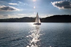 a sailboat on a lake with the sun reflecting on the water at Bezpieczna Przystań - Apartamenty-balia, sauna, narty in Uherce Mineralne