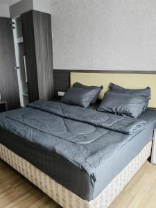 Cama grande con sábanas azules y almohadas grises en family 1 bed room apartment, en Melaka