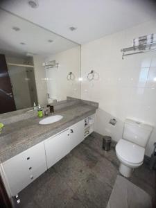 uma casa de banho com um WC, um lavatório e um espelho. em Brasil 21 suite flat em Brasília