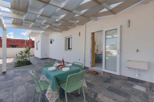 eine Terrasse mit einem grünen Tisch, Stühlen und einer Tür in der Unterkunft Villa Aleida by BarbarHouse in Punta Prosciutto