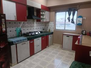 kuchnia z czerwono-białymi szafkami i oknem w obiekcie Your Right Place w mieście Guwahati